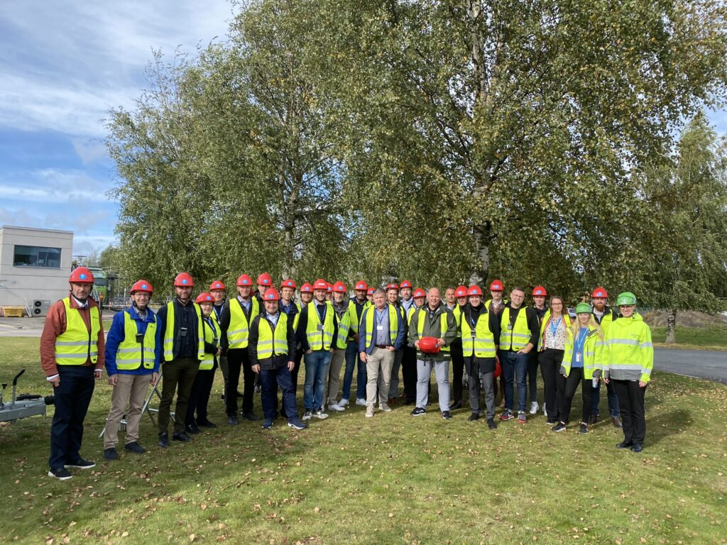 A group of people with yellow safety vests and red helmets.