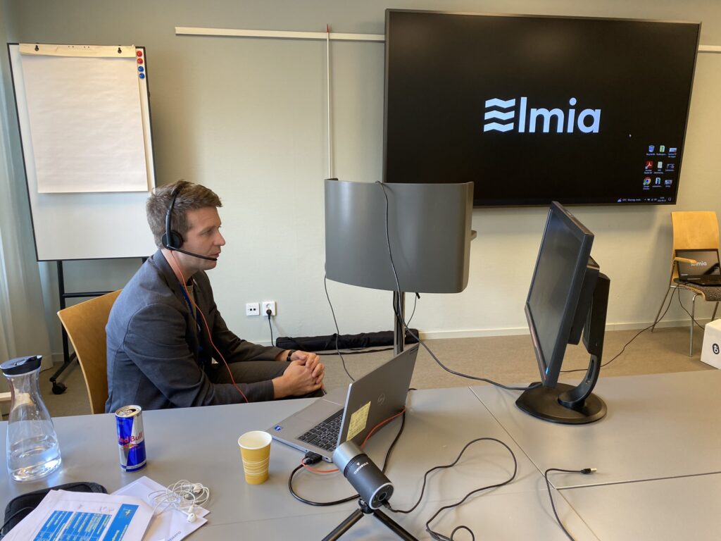A man sits by a computer with a headset.